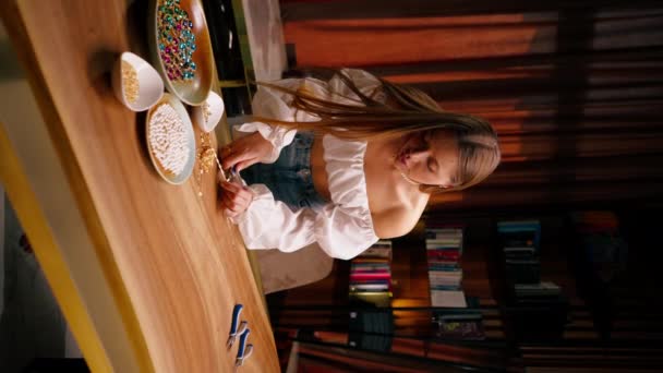 若い女の子がネックレスの工芸品の生産のための金のペンダントの残骸を切り取って自分の手でジュエリーを作る垂直ビデオ — ストック動画