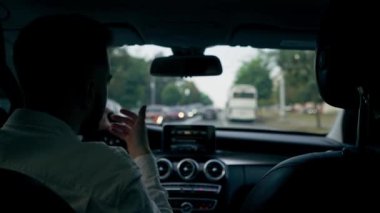 Bir adam, bir işadamı şehirde lüks bir araba kullanıyor. Siyah deri bir iç mekan, trafik sıkışıklığı.