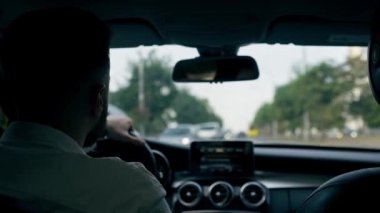 Bir adam, bir işadamı şehirde lüks bir araba kullanıyor. Siyah deri bir iç mekan, trafik sıkışıklığı.