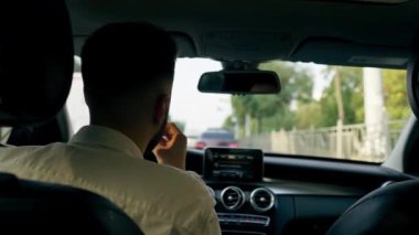 Bir adam, bir işadamı şehirde lüks bir araba kullanıyor. Siyah deri bir iç mekan, trafik sıkışıklığı.