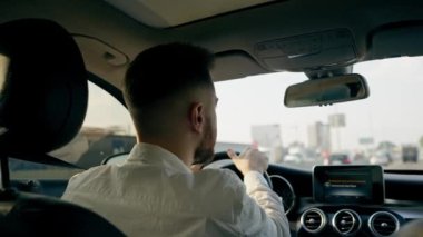 Bir adam, bir işadamı şehirde lüks bir araba kullanıyor. Siyah deri bir iç mekan, trafik sıkışıklığı.