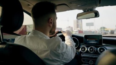 Bir adam, bir işadamı şehirde lüks bir araba kullanıyor. Siyah deri bir iç mekan, trafik sıkışıklığı.