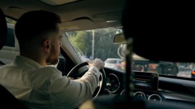 Bir adam, bir işadamı şehirde lüks bir araba kullanıyor. Siyah deri bir iç mekan, trafik sıkışıklığı.