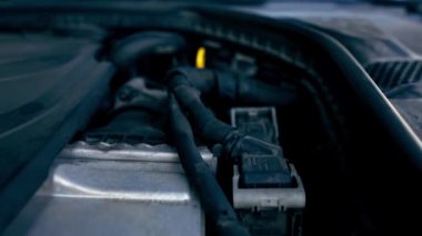 Arabanın kaputunun altındaki detayların yakın plan görüntüsü. Motor aküsü elektrik kabloları. Yağ vagonu tamiri.