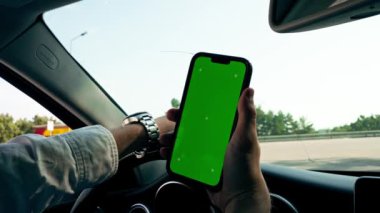 Arka plan yakın çekim sürücü direksiyon arkasında lüks araba elinde akıllı telefon yeşil ekran ile