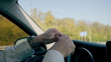 Şehrin içinde lüks bir arabanın içinde direksiyonun başında bir erkek sürücünün saatiyle el ele tutuşun.