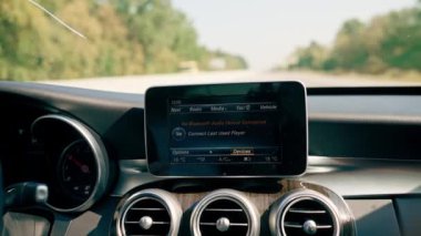 Lüks bir arabanın içi. Cihazı arabanın bluetooth sistemine bağlayan ekrana yakın çekim.