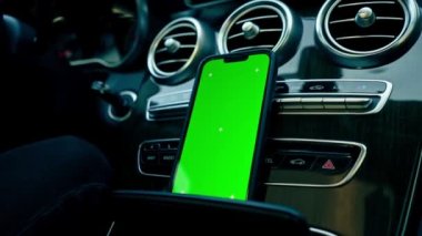 Yeşil ekran ekranlı bir telefonun yakın plan görüntüsü gösterge panelinde lüks otomatik bağlantı teknolojisiyle duruyor.