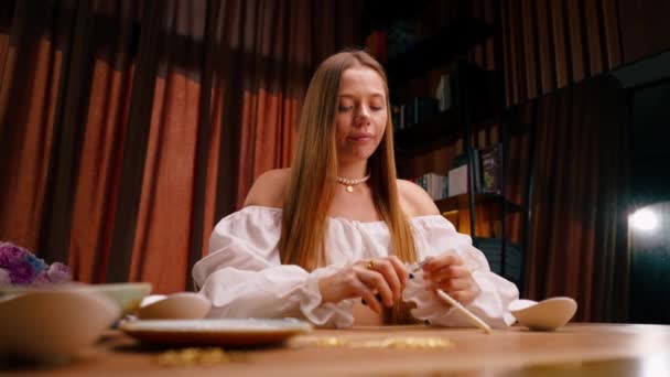 若い女の子は彼女自身の手でジュエリーを作り プライヤーの工芸品の生産でネックレスのためのワイヤーの残骸を切ります — ストック動画