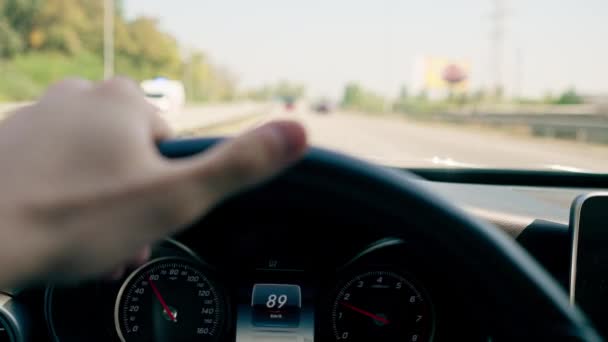 市内の高級車の運転の内部の車輪の後ろの男性の運転者の手のクローズアップ — ストック動画