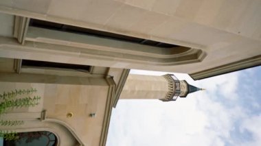 Müslüman camiinin avlusunda balkonu olan yüksek kule minaresi parlak bir gökyüzünün arka planında.
