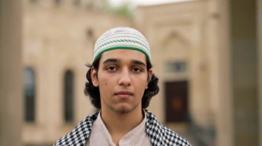 Ulusal giysili, boynunda tespihle caminin avlusunda dua eden bir Arap 'ın yakın plan portresi.