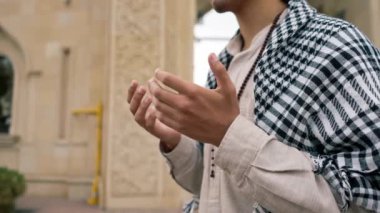 Ulusal giysili, boynunda tespihle caminin avlusunda dua eden bir Arap 'ın yakın plan portresi.