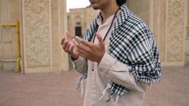 Ulusal giysili, boynunda tespihle caminin avlusunda dua eden bir Arap 'ın yakın plan portresi.