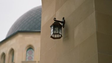 Avludaki Müslüman camiinin girişinin yakınındaki alanı aydınlatmak için kapatılmış cam bir lamba.