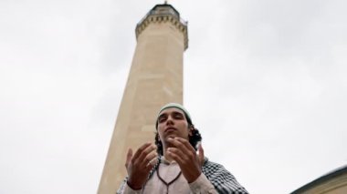 Ulusal giysili, boynunda tespihle caminin avlusunda dua eden bir Arap 'ın yakın plan portresi.