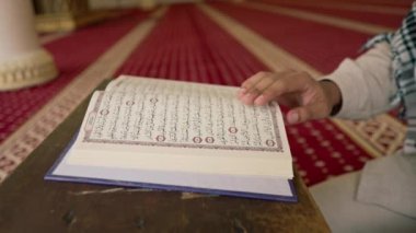Müslüman bir adam Kuran 'ı dikkatle okur ve camide Allah' a dua eder.