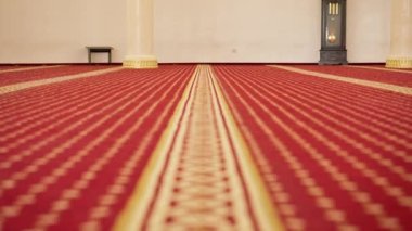 Müslüman camisinde namaz kılan büyük, boş, kırmızı halılı ve büyük pencereli bir ibadethane.