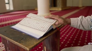 Müslüman bir adam Kuran 'ı dikkatle okur ve camide Allah' a dua eder.