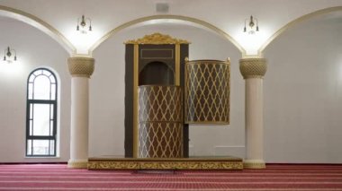 Müslüman camisinde namaz kılan büyük, boş, kırmızı halılı ve büyük pencereli bir ibadethane.