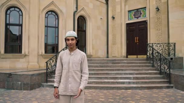 彼の首の周りのローズマリーがモスクの中庭で祈る国民服でアラブの外観の男 — ストック動画