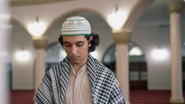 Ulusal giysili, boynunda tespihle caminin avlusunda dua eden bir Arap 'ın yakın plan portresi.