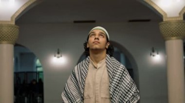 Müslüman bir adam camideki ibadet salonunun ortasında başı dik bir şekilde duruyor.