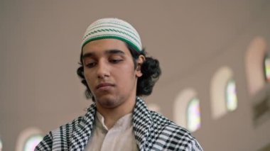 Ulusal giysili, boynunda tespihle caminin avlusunda dua eden bir Arap 'ın yakın plan portresi.