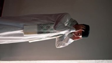 Ulusal giysilere inanan bir inanan camiinin penceresinin yanındaki alacakaranlıkta dua eder ve Allah 'a döner.