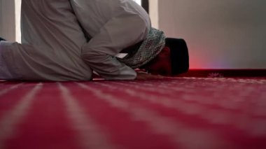 Müslüman adam Ramazan 'da diz çöküp dua ediyor ve İslami tapınaktaki destek ve ruhsal refah için teşekkür ediyor.