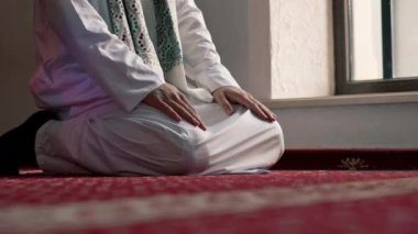 Müslüman adam Ramazan 'da diz çöküp dua ediyor ve İslami tapınaktaki destek ve ruhsal refah için teşekkür ediyor.