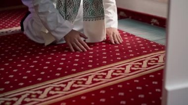 Müslüman adam Ramazan 'da diz çöküp dua ediyor ve İslami tapınaktaki destek ve ruhsal refah için teşekkür ediyor.