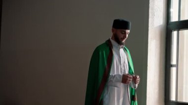Bir Arap rahibin silueti, ulusal giysiler içinde bir camide duruyor ve Kuran 'ın yardımıyla Ramazan' da Allah 'a dua ediyor.