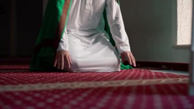 Müslüman adam Ramazan 'da diz çöküp dua ediyor ve İslami tapınaktaki destek ve ruhsal refah için teşekkür ediyor.