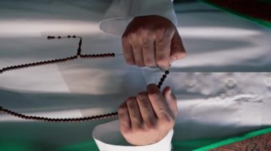 Dönüşüm ve Allah 'a ibadet sırasında tespih tutan Müslüman bir adamın elleri.