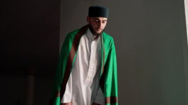 Ulusal giysilere inanan bir inanan camiinin penceresinin yanındaki alacakaranlıkta dua eder ve Allah 'a döner.