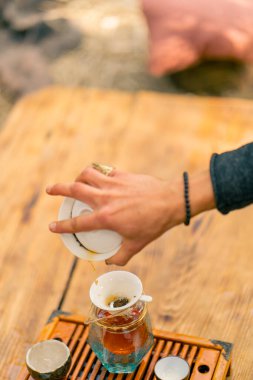 Geleneksel çay seremonisi sırasında demlenmiş doğal Çin çayının küçük bir cam çaydanlığa döküldüğü yakın çekim.