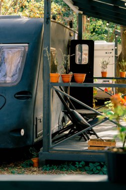 Barbekü alanı olan küçük bir teras ve bir tatil evinin yanında açık hava eğlencesi için karavan şeklinde sandalyeler.