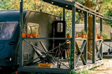 Barbekü alanı olan küçük bir teras ve bir tatil evinin yanında açık hava eğlencesi için karavan şeklinde sandalyeler.