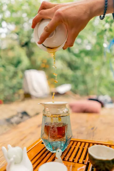 在一个茶道仪式上 一个男人从高处向杯子茶壶里倒入自制茶的特写镜头 — 图库照片