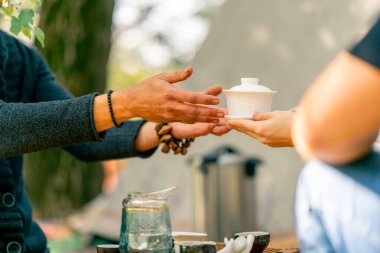 Geleneksel çayı tatması için bir kase sıcak içeceği bir kıza uzatan bir çay ustasının ellerinin yakın plan çekimi.