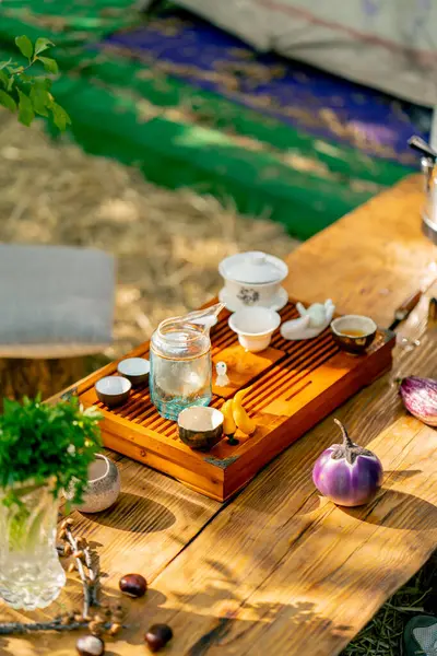 A wooden stand with bowls filled with water and cups of tea stands on the table among greens and vegetables