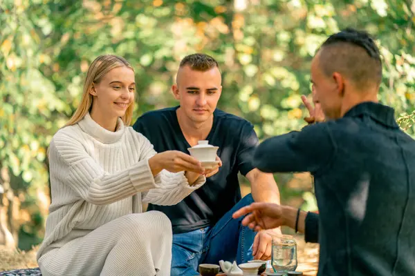 Profesyonel bir çay ustası, çay tatmak için genç bir çifte kapaklı bir fincan çay verir.