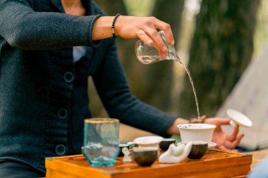 Çay seremonisinde çay yapmak için bir adamın eli seramik kaselere kaynar su döker.