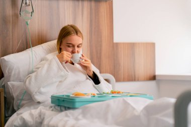 Hastane koğuşundaki bir kız, iyileşmesi ve iyileşmesi için personelin ona getirdiği sağlıklı yiyecekleri yiyor.