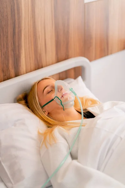 Close-up shot of a young girl lying in intensive care in an oxygen mask in a hospital to maintain the health and life of the patient