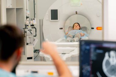 Bir kız vücudunu incelemeden önce MR makinesinde yalan söyler ve radyoloji uzmanı teşhisi koyması için ona emir verir.