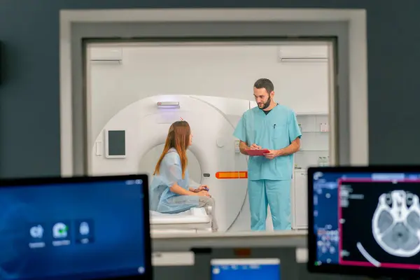 Monitors with diagnostics against the background of a doctor communicating with a patient before computed tomography examination