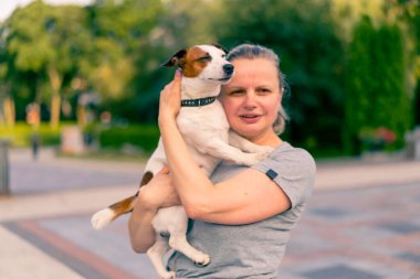 Küçük köpeği Jack Russell Terrier 'ı tutan bir kadının portresi. Bakım hayvanları, arkadaşlık.