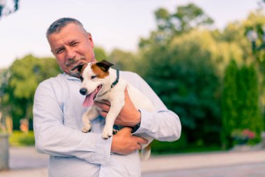 Yetişkin sakallı bir adamın portresi. Küçük köpeğini tutuyor. Jack Russell Terrier cinsi.